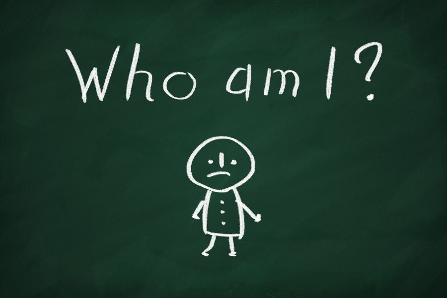 "Who am I?" on a chalkboard with a chalk person drawn with a slight frowny face