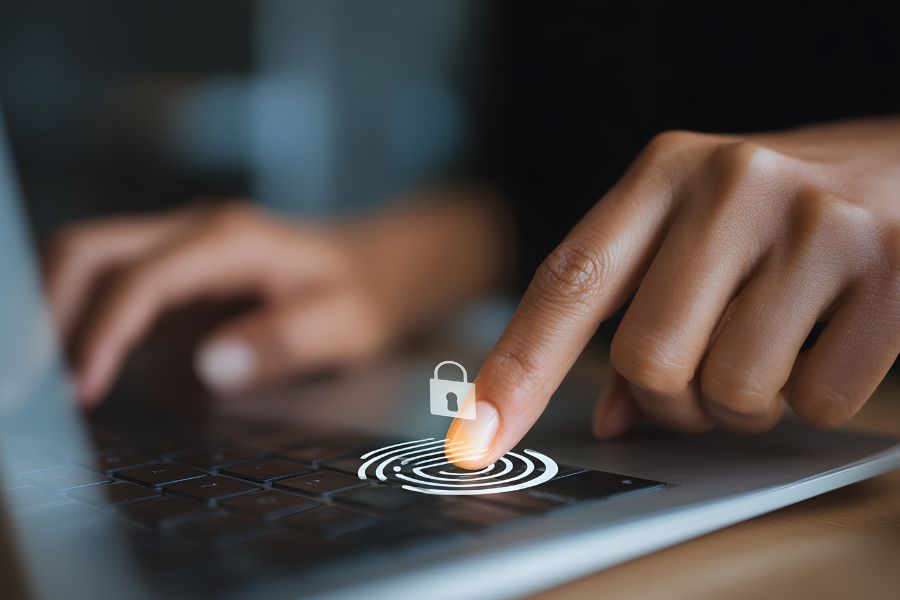 User placing their finger on a biometric scanner on a laptop